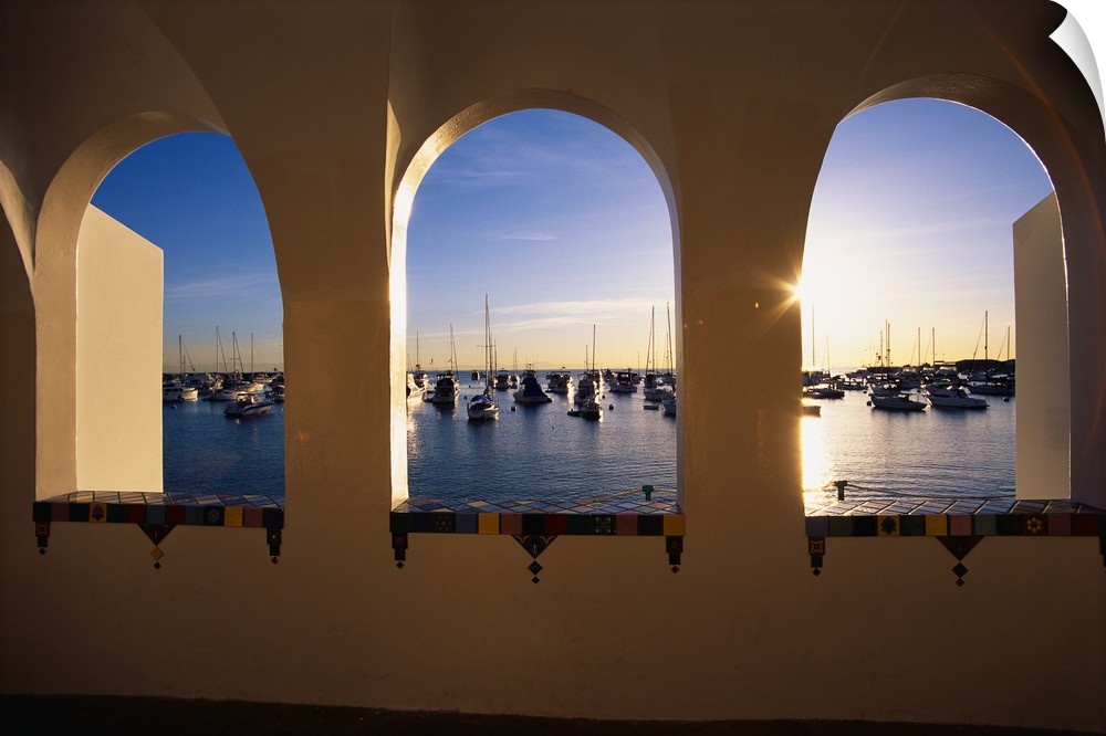 Big, landscape photograph looking through three windows at the Catalina Casino, numerous boats sitting in the water of the...