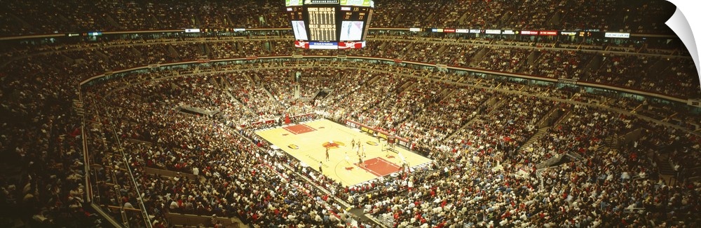 A large panoramic photograph taken inside the Chicago Bulls stadium. The seats are filled with fans as they watch the game.