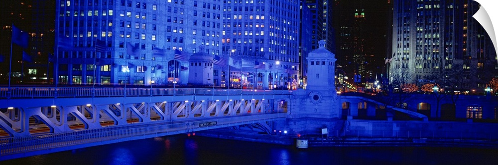 Panoramic view of the Michigan Avenue Bridge during the night. The buildings in the background and the bridge are lit up.