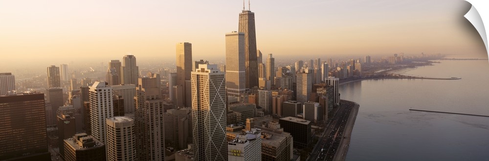 High angle panoramic photograph taken of the skyscrapers in Chicago during sunrise with the lake pictured just to the right.