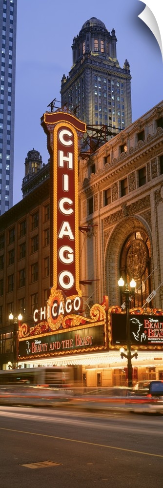 Vertical panoramic photograph of downtown theater with lit up marquee.  There is a skyscraper in the background and light ...