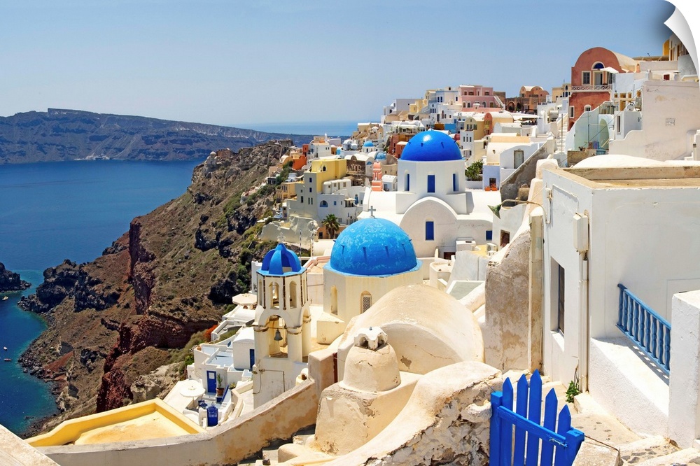 This hillside city with its famous colored roof tops overlooks a rocky Grecian sea in this panoramic photograph.