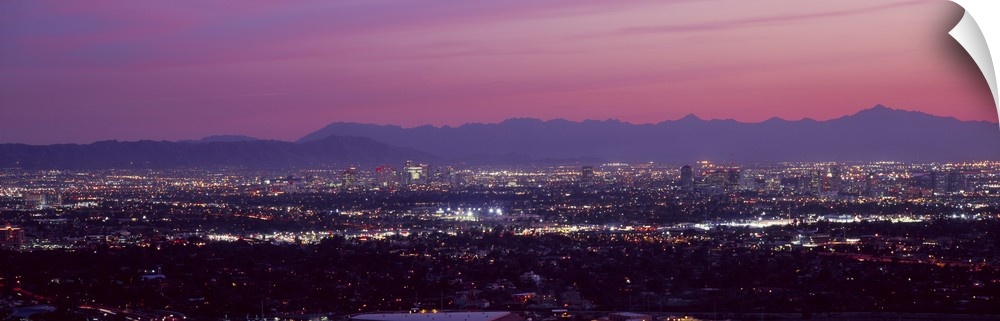 The city of Phoenix is illuminated under a dusk sky and shot in a panoramic view to show majority of the city.
