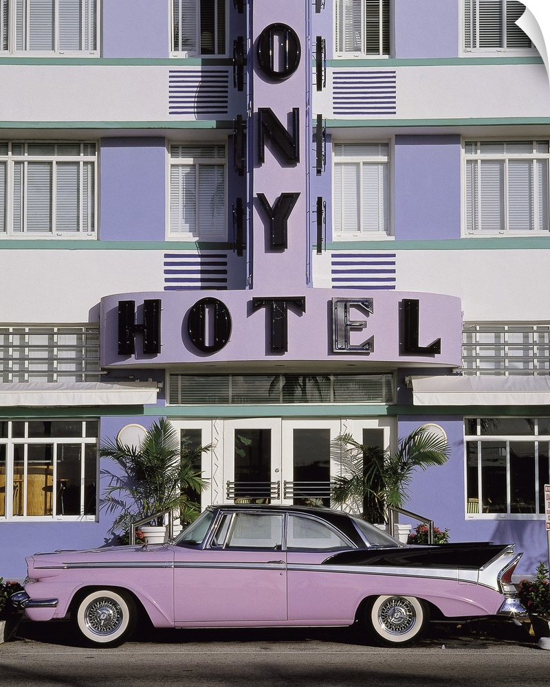 Vertical photograph on a large wall hanging of an old, classic car parked beneath the sign for the Colony Hotel, along Mia...
