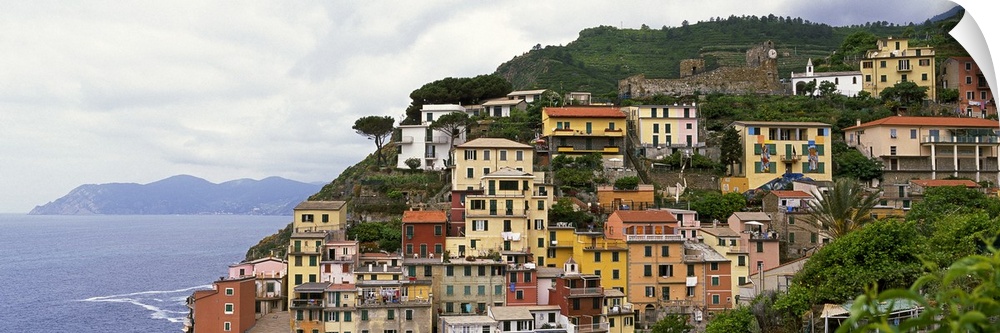 This panoramic landscape photograph of homes built into the hillside overlooking the sea.