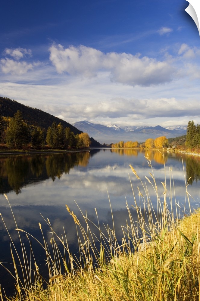 Clouds and distant snowcapped mountains reflected in Kootenai River, Montana