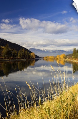 Clouds and distant snowcapped mountains reflected in Kootenai River, Montana