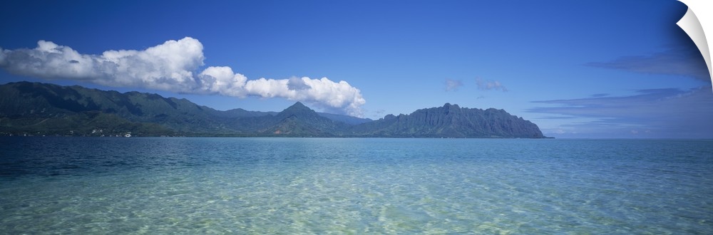 Panoramic view of the tropical ocean surface of the Pacific, with tall mountains and clouds on the horizon.