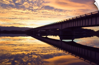 Cloudy sunset sky over bridge, reflection in Flathead River, Montana