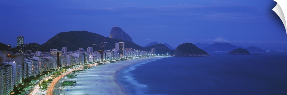 A large panoramic shot of the coast and skyline of Rio De Janeiro. Taken at dusk, the buildings and streets are lit up wit...