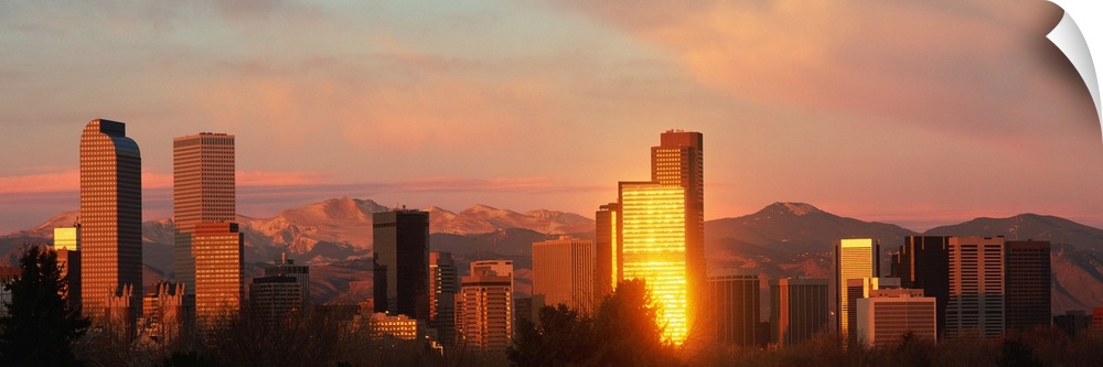 A panoramic shot taken of the Denver skyline while the sun is setting and reflecting off some of the buildings.