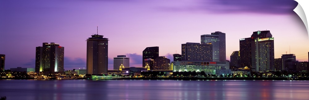 Sunset panorama of the Downtown New Orleans skyline with the Mississippi River in the foreground.
