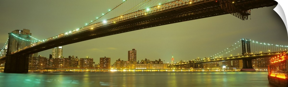 Illuminated New York City skyline and suspension bridges over the East River.