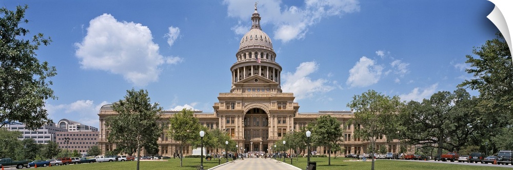 The state capitol building in Texas is photographed in wide angle view showing the pathway and trees that line it going up...