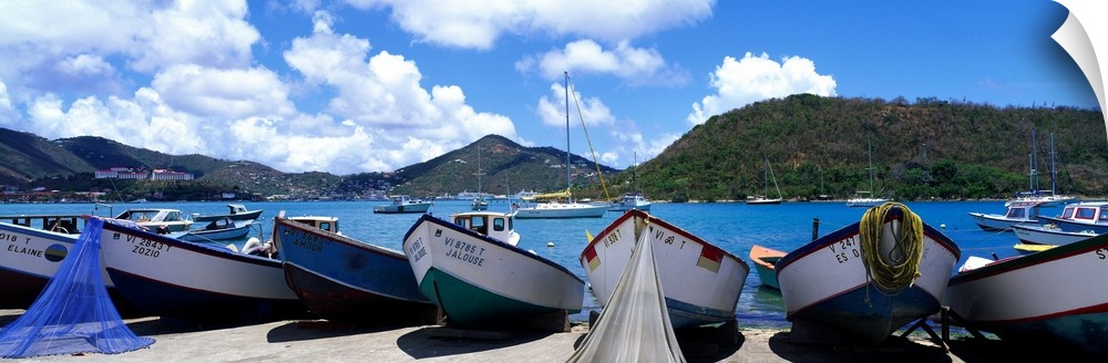 Panoramic photograph taken of boats out of the water. Behind them is the ocean water and the tall cliffs in St. Thomas.