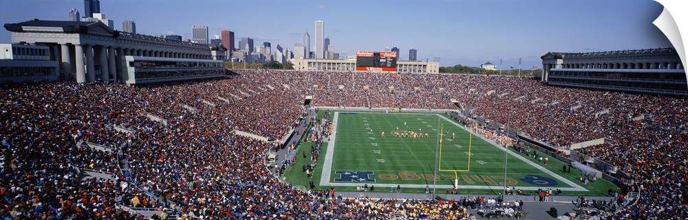 Panoramic photograph of NFL stadium with the city's skyline in  the distance under clear skies.  The arena is filled with ...