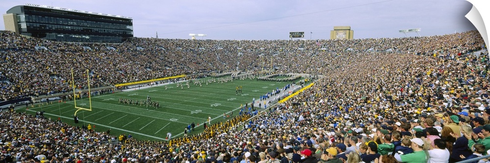 Wide angle photograph of Notre Dame Stadium, full of fans during a football game, in South Bend, Indiana.