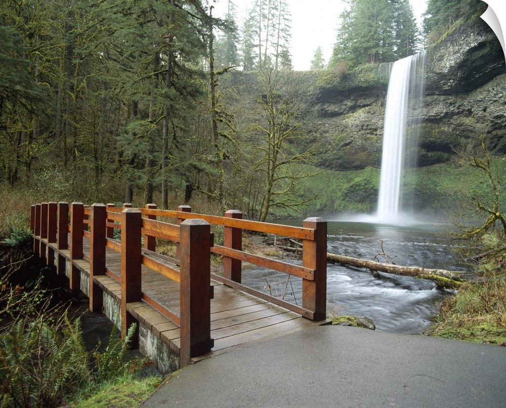Large wall docor of a wooden bridge going across a river with a thin waterfall on the right.