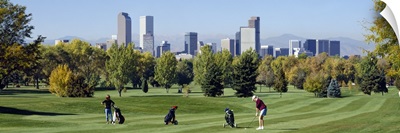 Four people playing golf with buildings in the background, Denver, Colorado