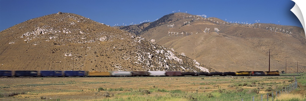 Speeding train and mountains. Speeding train at base of mountains with wind turbines in Tehachapi, CA.