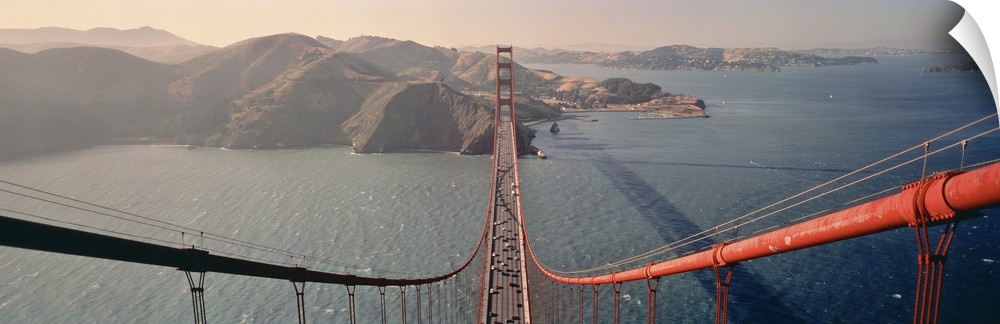 A wide angle photograph taken from on top of the golden gate bridge while looking down the cables and onto the mountainous...