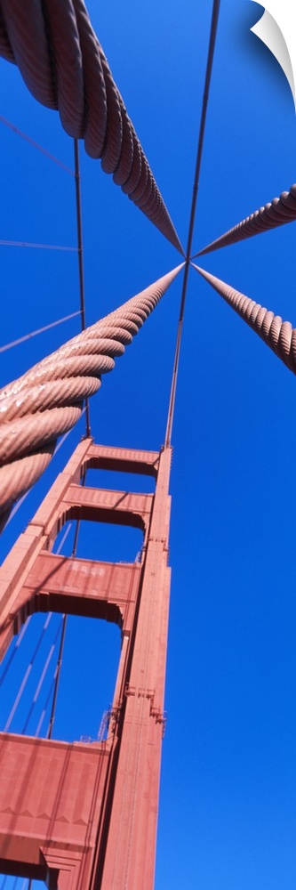Up-close vertical panoramic photograph of bridge spire and cables under a clear sky.
