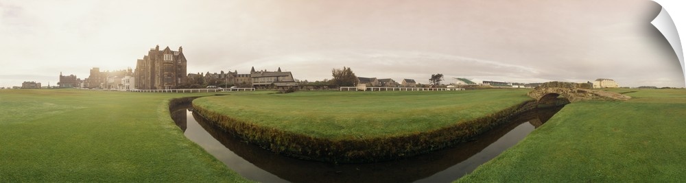 Large fish-eye panoramic photo of the St. Andrews golf course with the magestic stone club house in the background.