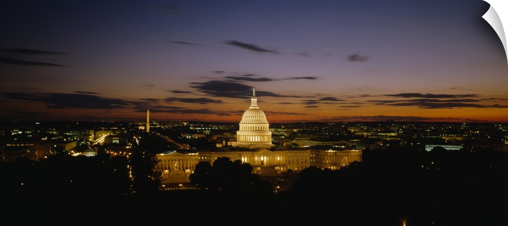An aerial shot taken at a distance of the capitol building illuminated under a sunset sky.