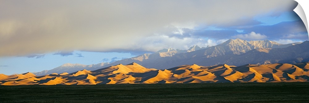 Sand dunes in a desert with a mountain range in the background, Great Sand Dunes National Park, Colorado, USA