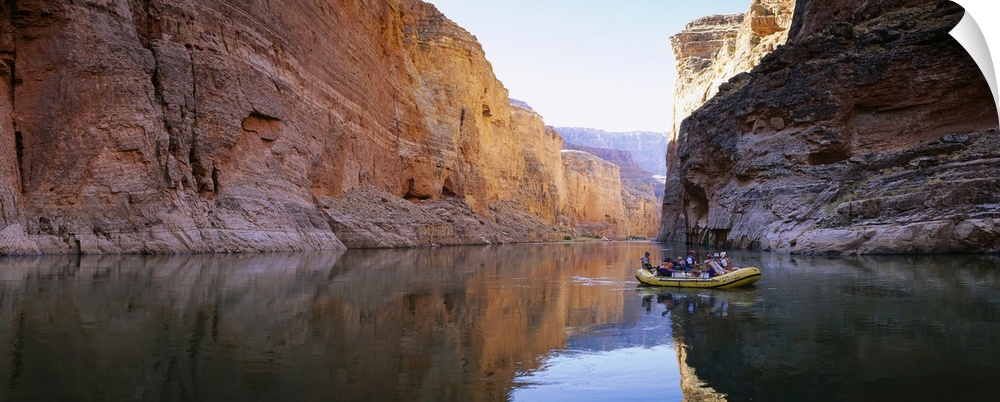 Large panoramic shot of an inflatable raft drifting down the tranquil Colorado River in the Grand Canyon.