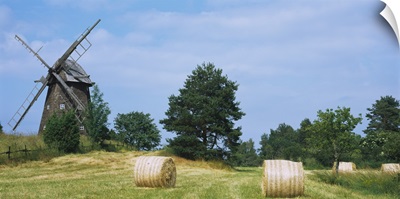 Hay bale in a field with a traditional windmill in the background, Riddarfjarden, Narke, Sweden