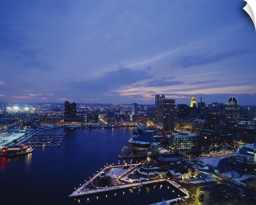 Large photograph taken from an aerial view over the calm waters of the Inner Harbor within a busy city in the Northeastern...