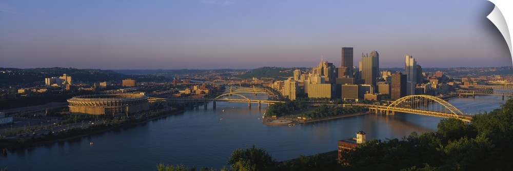 Panoramic photo of the Pittsburgh skyline bathed in morning light, showing skyscrapers and two bridges over the Allegheny ...