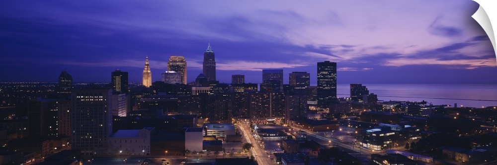 Panoramic, large photograph from a high angle of the Cleveland skyline, with lit buildings at night.