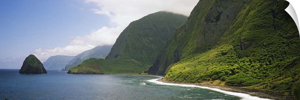 Wide angle photograph taken of immense cliffs that line the coast of a Hawaiian island.