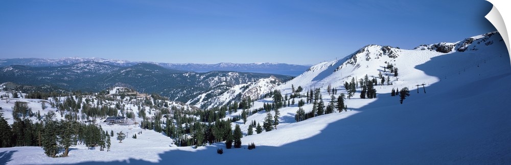 A panoramic photograph looking down a snow covered mountain into the valley below.