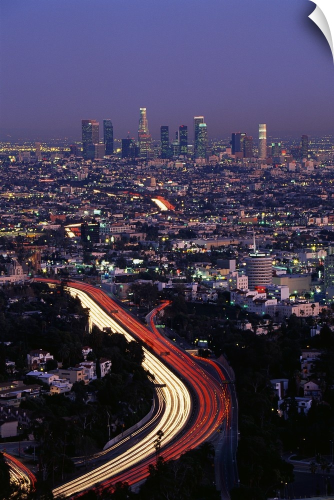 Vertical panoramic of highway running through busy west coast metropolis with city skyline in distance at dusk.  The highw...