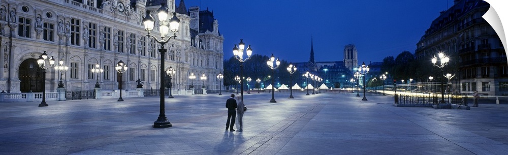 Panoramic image of a street outside the Hotel de Ville lit up at night in Paris, France.