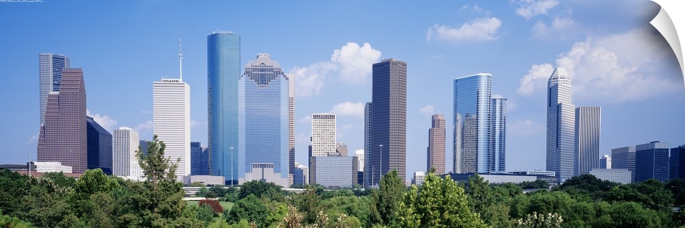 Panoramic photo of the Houston cityscape against a blue sky.