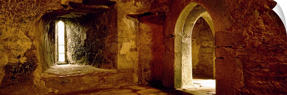 Panoramic photograph of the inside of an old stone palace with arched doorways.