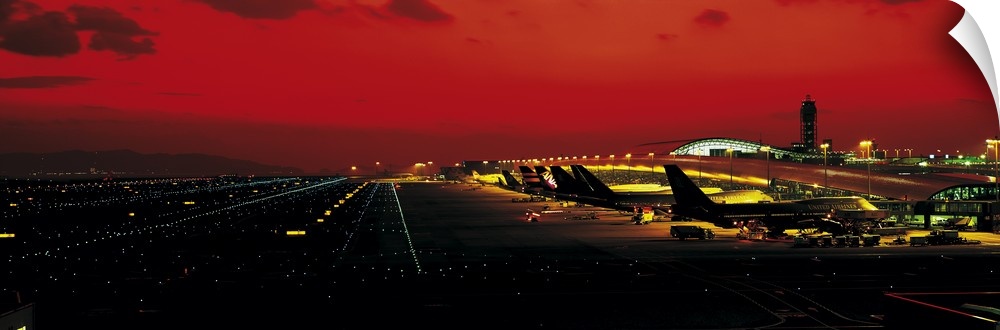 High angle photograph on a horizontal wall hanging of a line of aircraft surrounded by the lights and runway at Kansai Int...