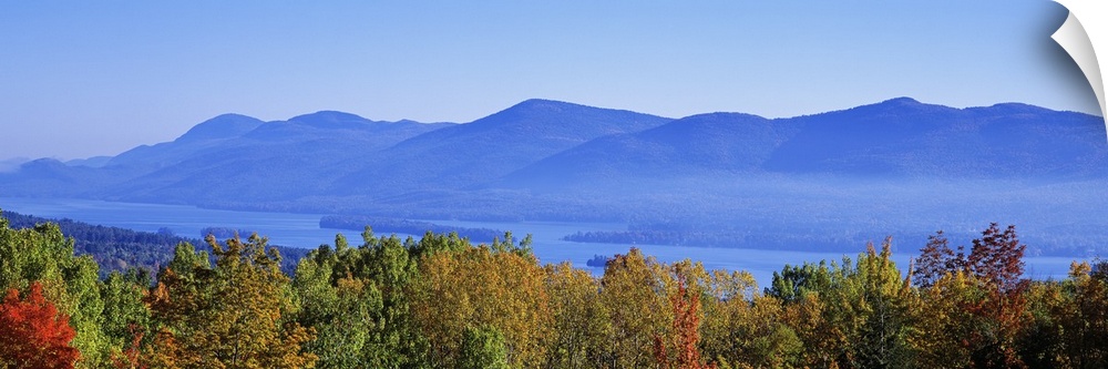 Panoramic photograph on a large wall hanging of the tops of autumn trees in front of Lake George, the Adirondack Mountains...
