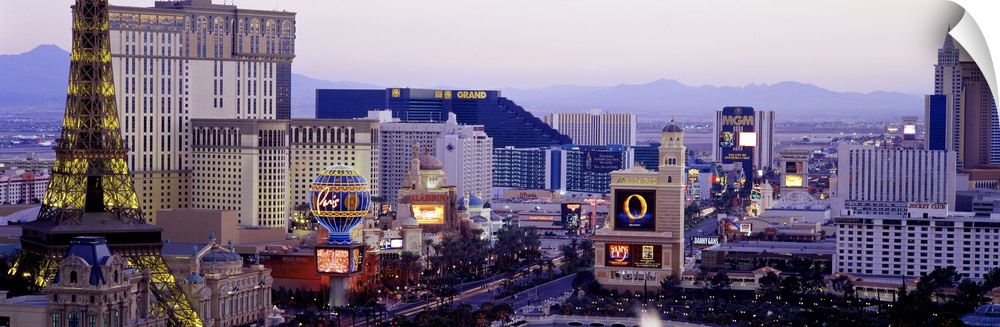 Panoramic photograph of ""Sin City"" skyline with mountains in the distance.  The buildings are lit up and the neon signs ...
