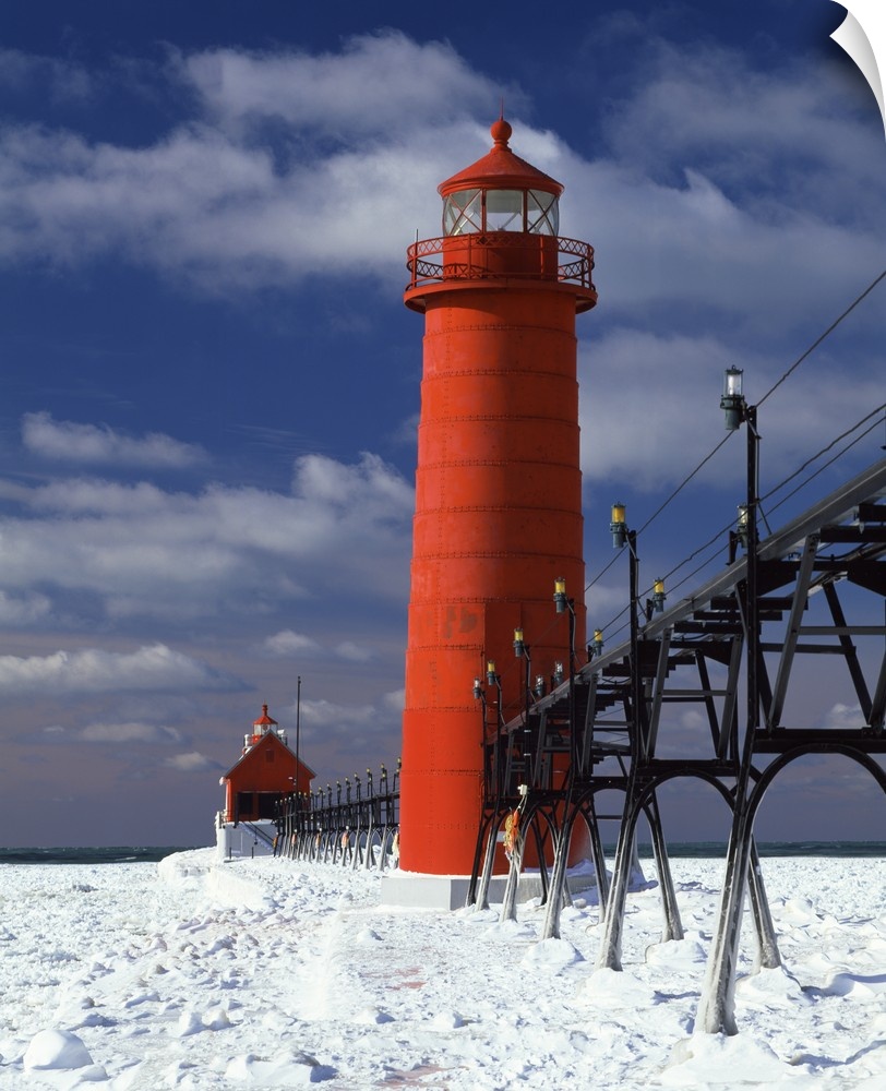 A lighthouse in Michigan is photographed closely as snow covers the ground surrounding it.