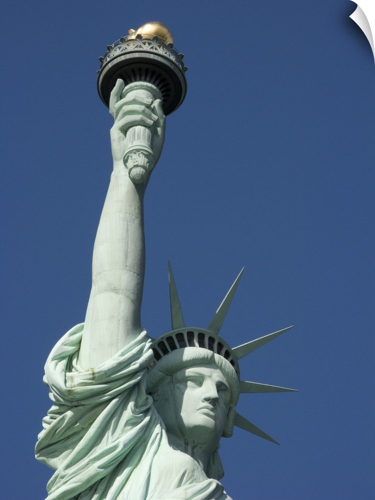 Photograph taken from below the statue of liberty that shows her from the chest and up.