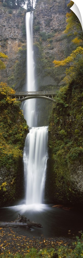 Vertical panoramic photograph of two large waterfalls, one feeding in to the other, and an arched bridge spanning one side...