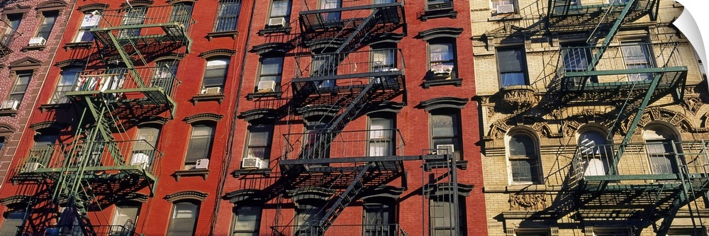 Panoramic image of iron fire ladders on the sides of apartment buildings in an urban city, creating industrial patterns.