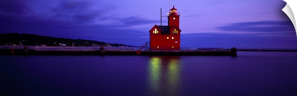 A brightly colored lighthouse reflecting light onto the water at night in Holland, Michigan.
