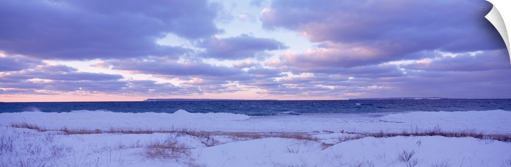 Large, wide angle photograph of a beach off of Lake Michigan, under a sky of pastels and clouds at sunset.