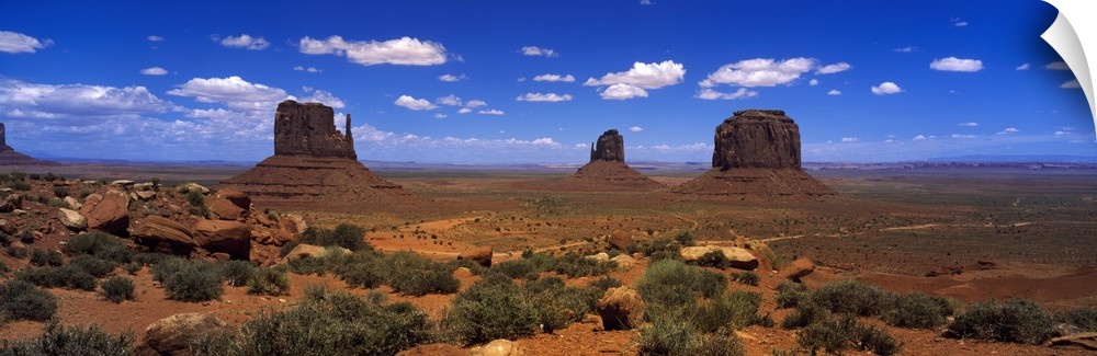 Panoramic photo on canvas of three tall rock formations in the desert under a bright blue sky.
